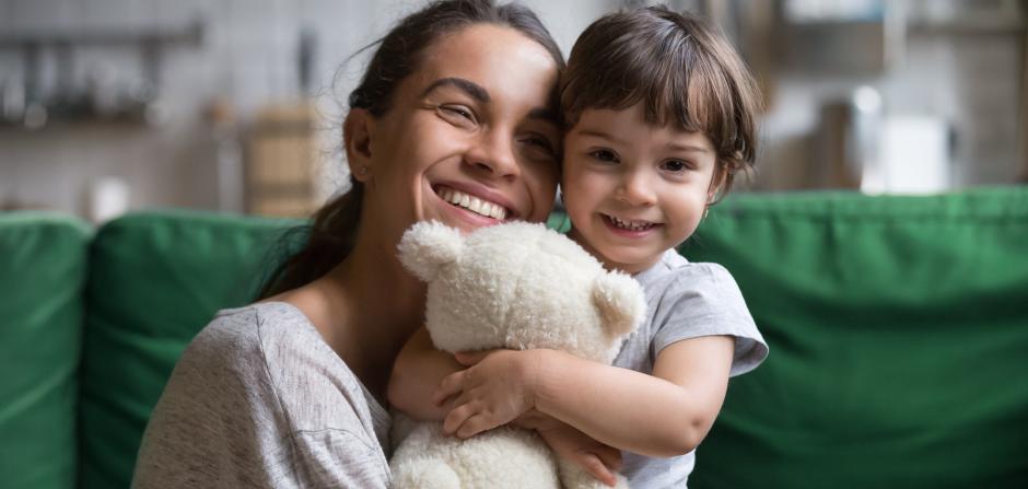 mother hugging child holding stuffed bear